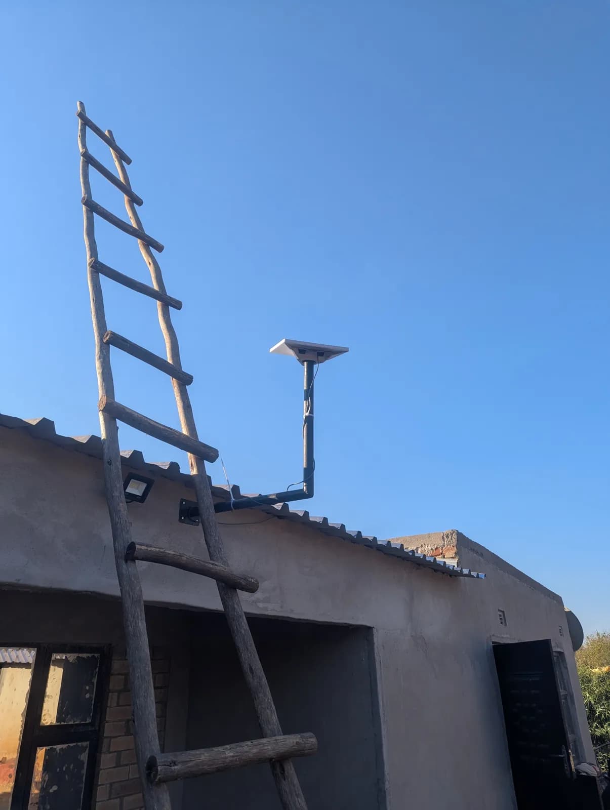 Raised Starlink pole mount on a flat roof, with a ladder for access, in Zimbabwe